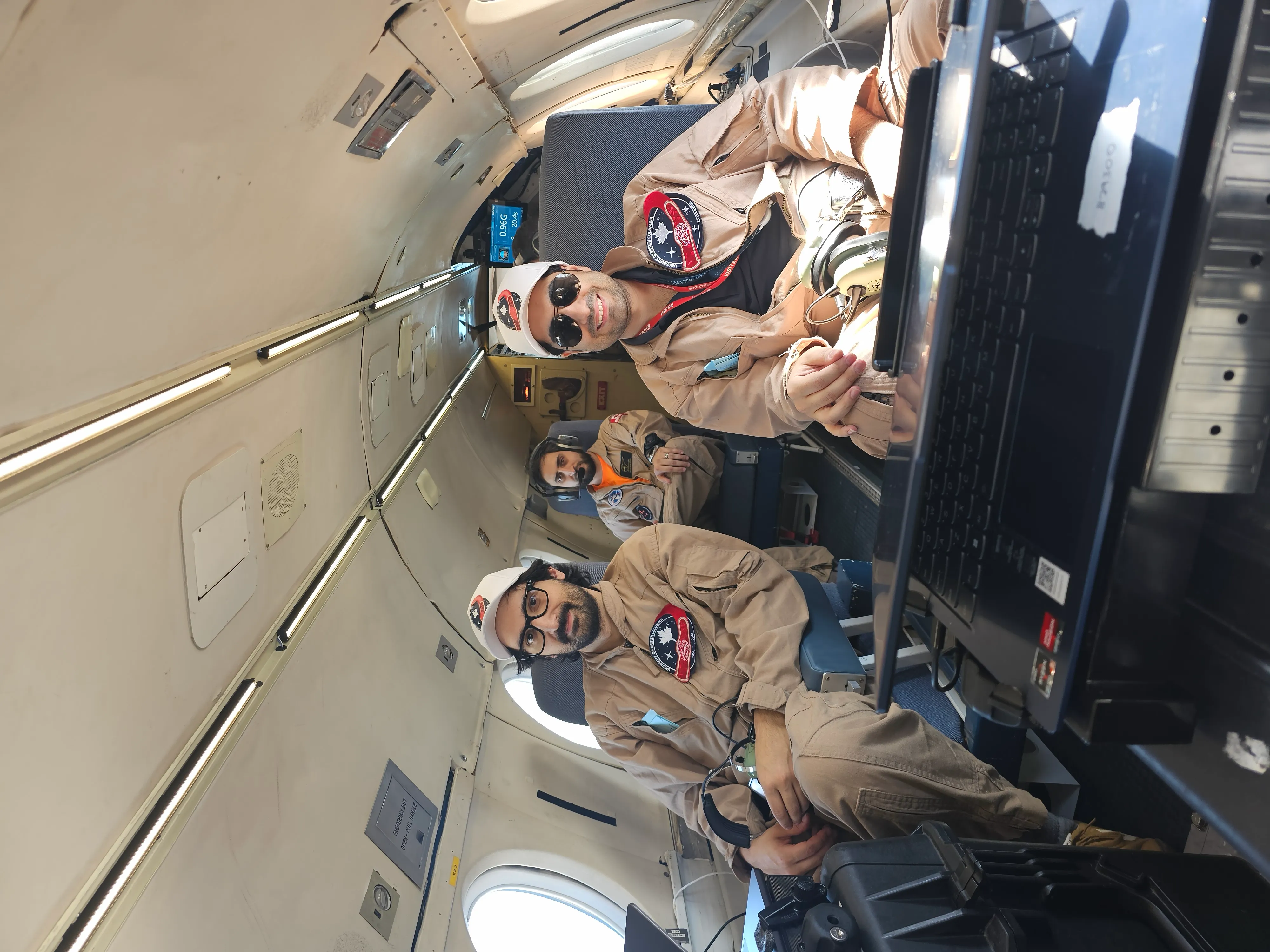 CLOT-LESS team members in flight suits seated beside the experiment laptop inside the aircraft.