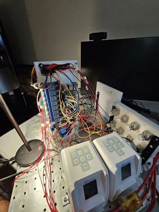 The relay module and wiring harness mounted vertically above the two peristaltic pumps on the payload baseplate.