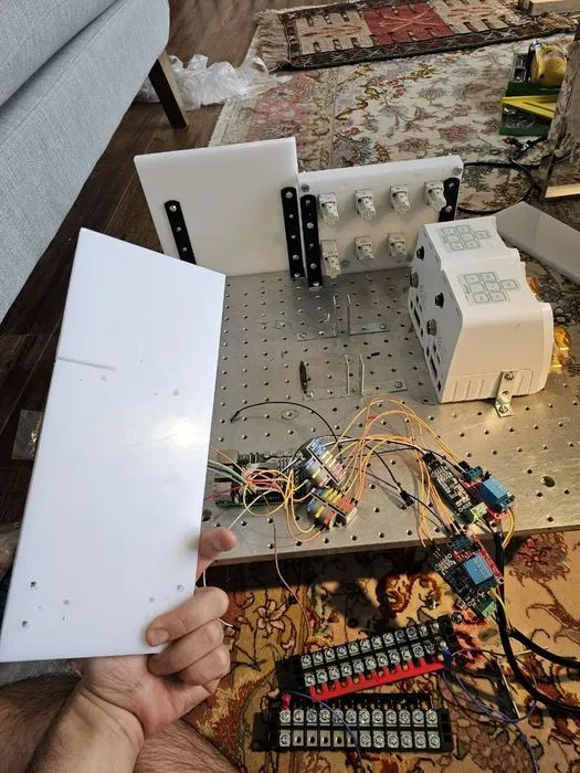 A machined HDPE plate held up during fabrication, drilled for the control electronics.